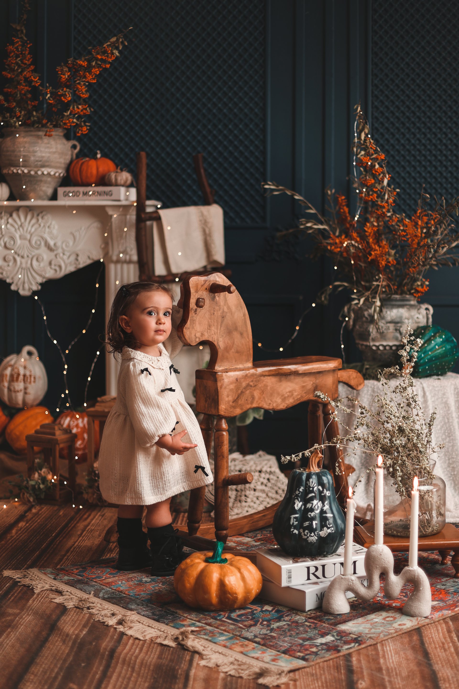 کودک ایستاده در دکور پاییزی کنار اسب چوبی