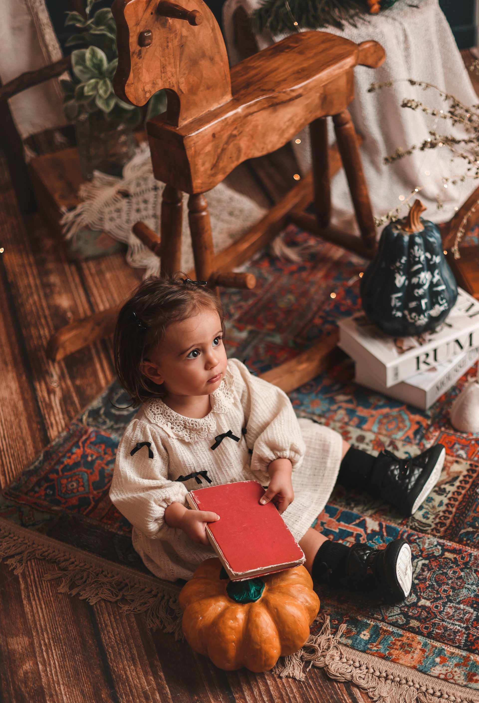 کودک نشسته روی فرش با کتاب و کدو